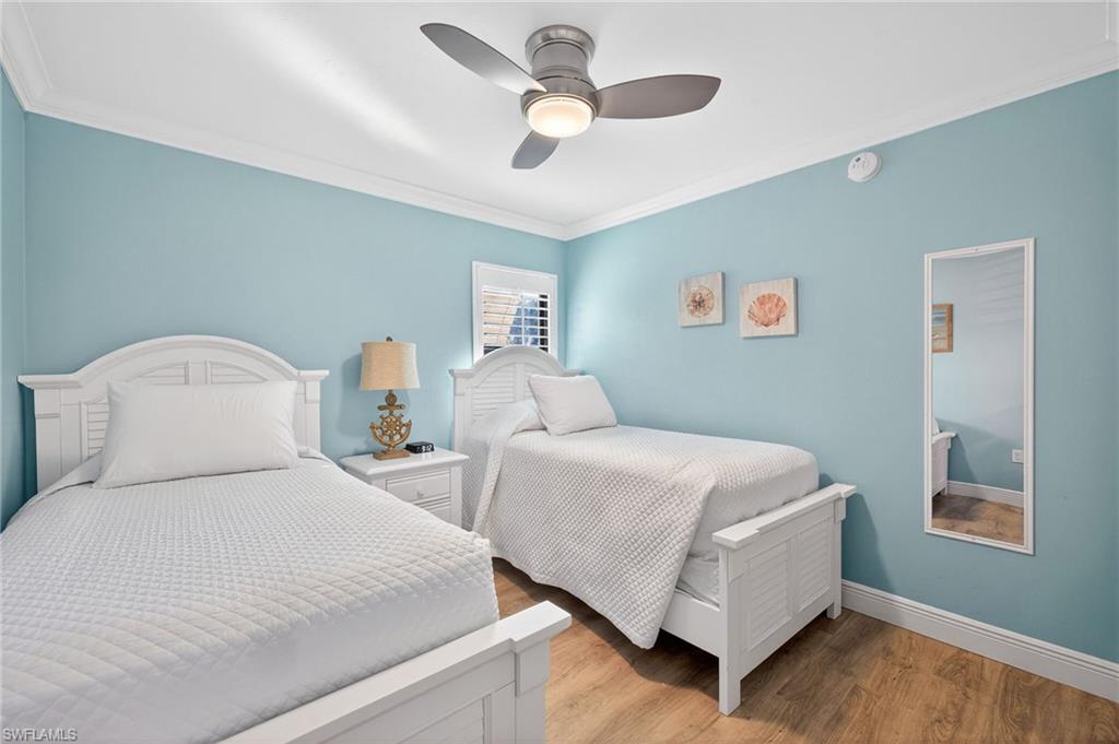 Bedroom featuring light wood-type flooring, ornamental molding, and a ceiling fan