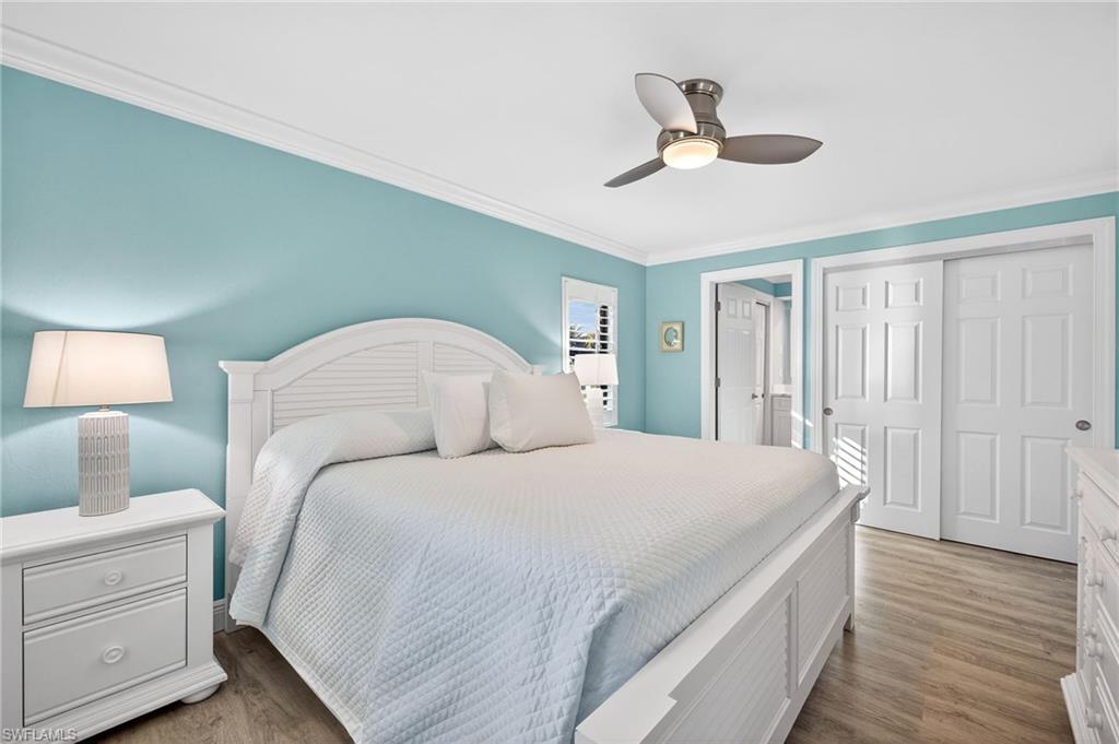 Primary Bedroom with crown molding, light wood-style floors, a closet, and a ceiling fan