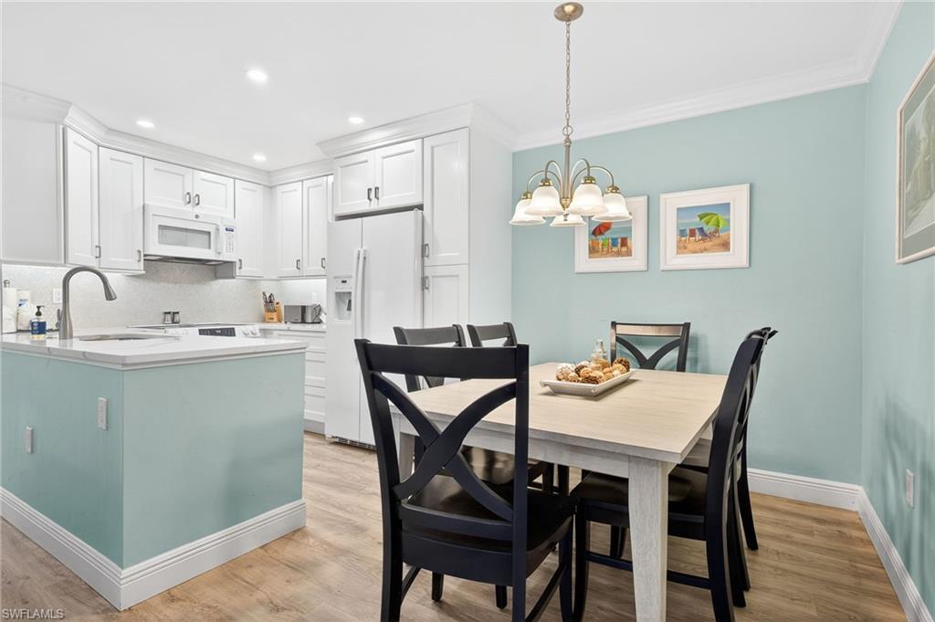 Dining room with light wood-style floors, suspended lighting, and crown molding