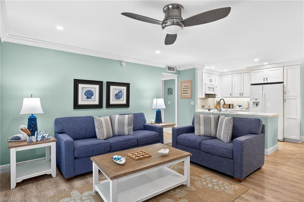 Living room with recessed lighting, crown molding, light wood-style flooring, and ceiling fan