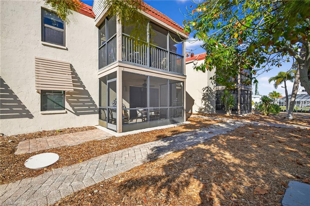 Back of house featuring a sunroom, stucco siding, a tiled roof, and a balcony