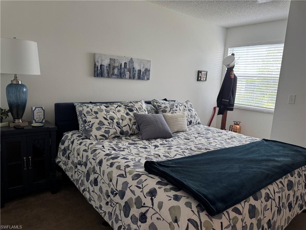 Bedroom with dark colored carpet and a textured ceiling