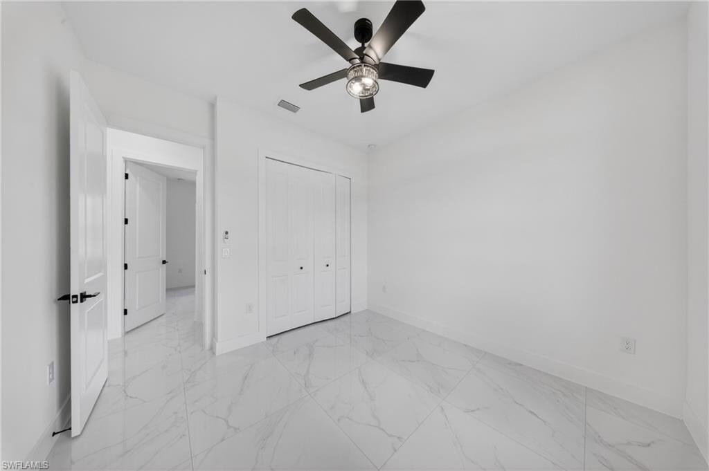 Room featuring marble-look floor tile, a modern ceiling fan with integrated lighting, white paneled doors with black hardware, and bi-fold closet doors