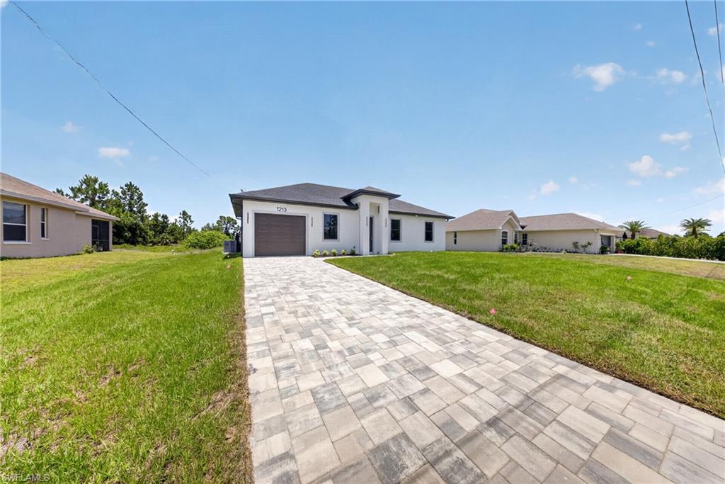 Contemporary single-story residence with a stucco exterior, dark shingle roof, and a prominent paver driveway
