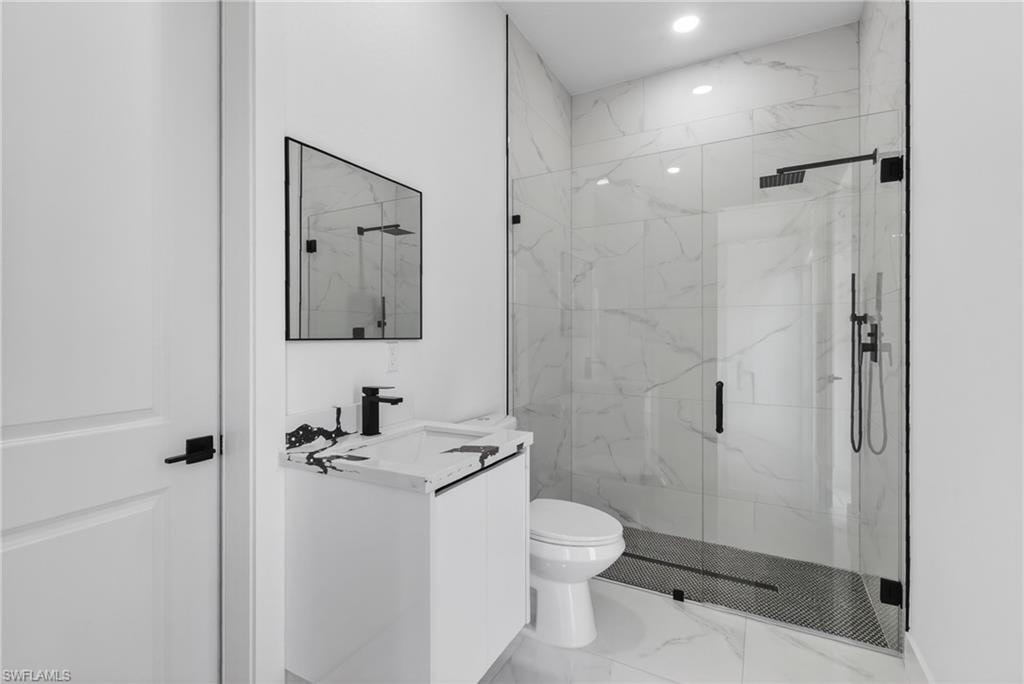 Bathroom featuring a glass-enclosed shower with black fixtures and a patterned floor