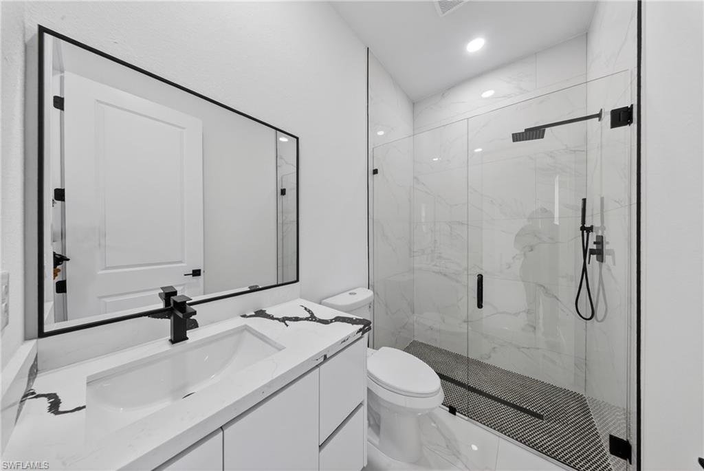 Contemporary bathroom featuring a frameless glass shower enclosure, white and gray veined wall tile, and a black mosaic tile shower floor