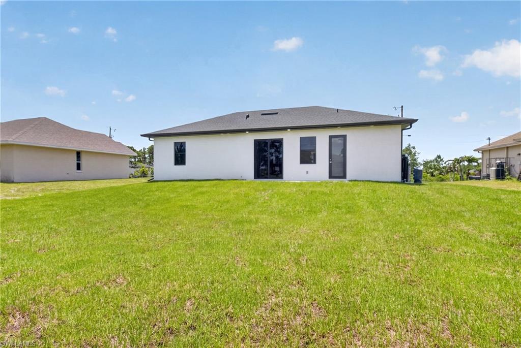 Expansive rear yard featuring a newly constructed white stucco exterior