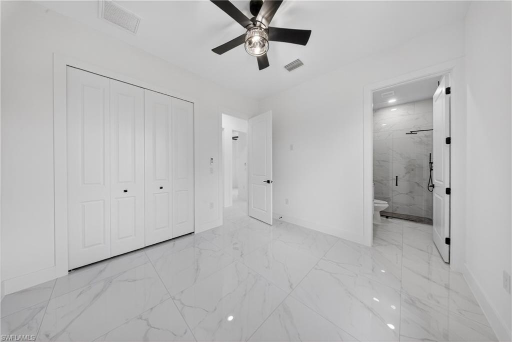 Spacious room featuring large format white tile flooring, a modern ceiling fan with integrated lighting, and white bi-fold closet doors