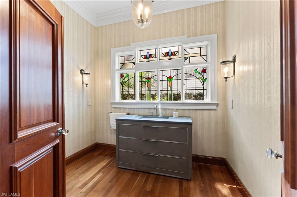 Entryway with ornamental molding, dark wood-style flooring, a sink, wallpapered walls, and baseboards