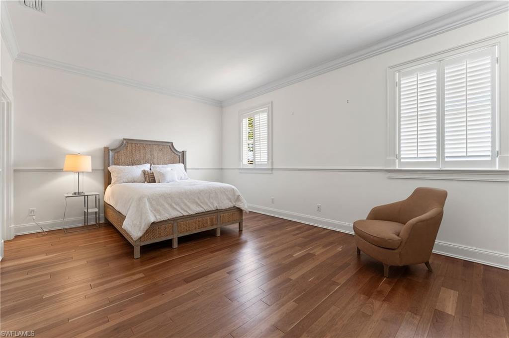 Bedroom featuring wood finished floors, baseboards, ornamental molding, and visible vents