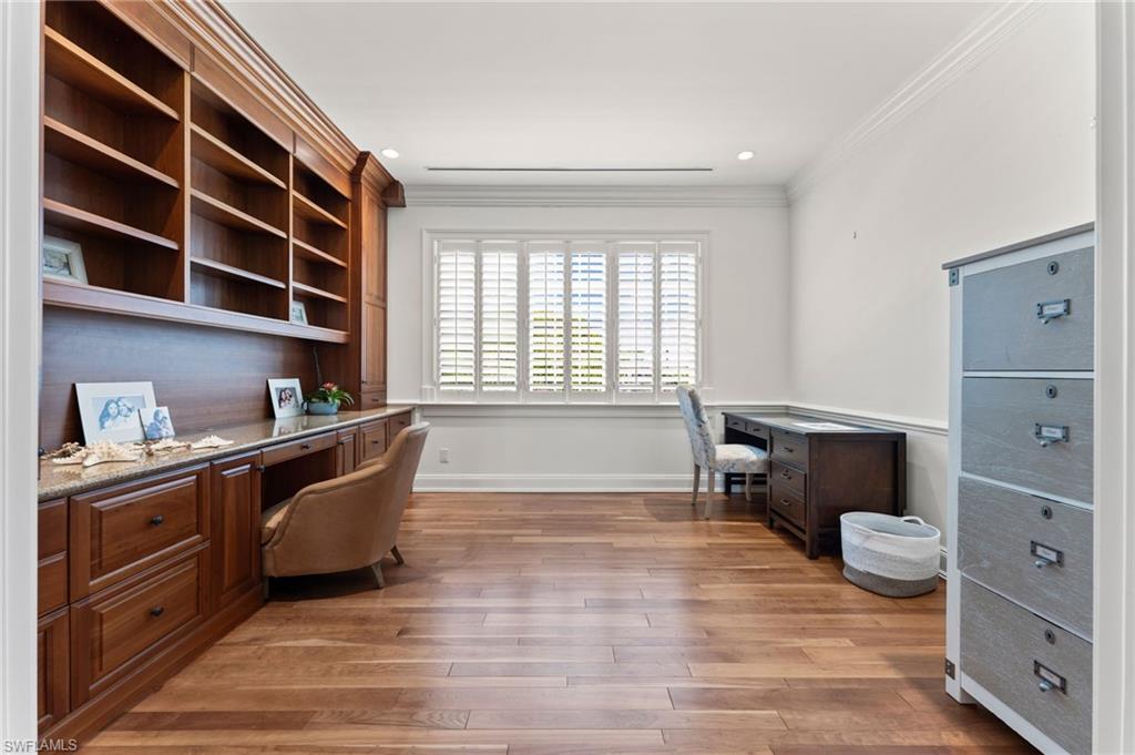 Office space with crown molding, baseboards, light wood-type flooring, and built in desk