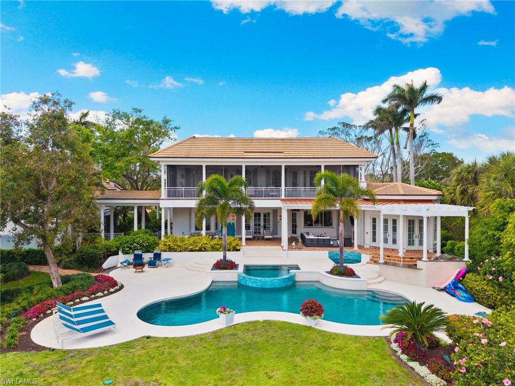 Rear view of house with a patio, french doors, a pool with connected hot tub, a sunroom, and a lawn