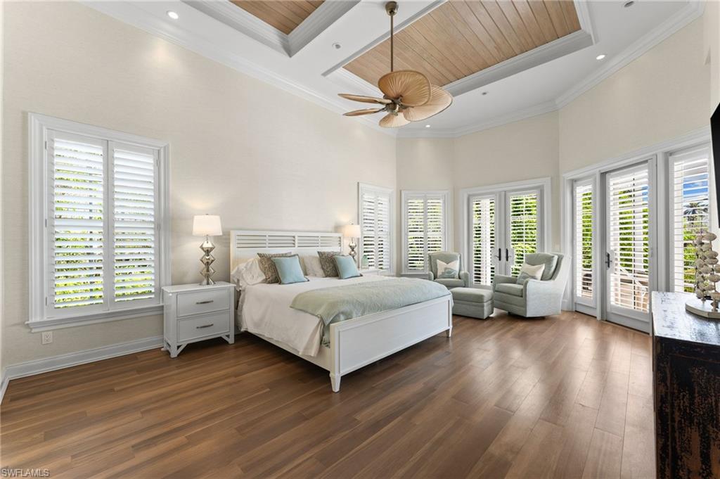 Bedroom featuring dark wood-type flooring, access to outside, multiple windows, and a high ceiling