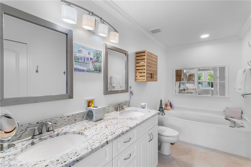 Full bath featuring a sink, double vanity, and crown molding