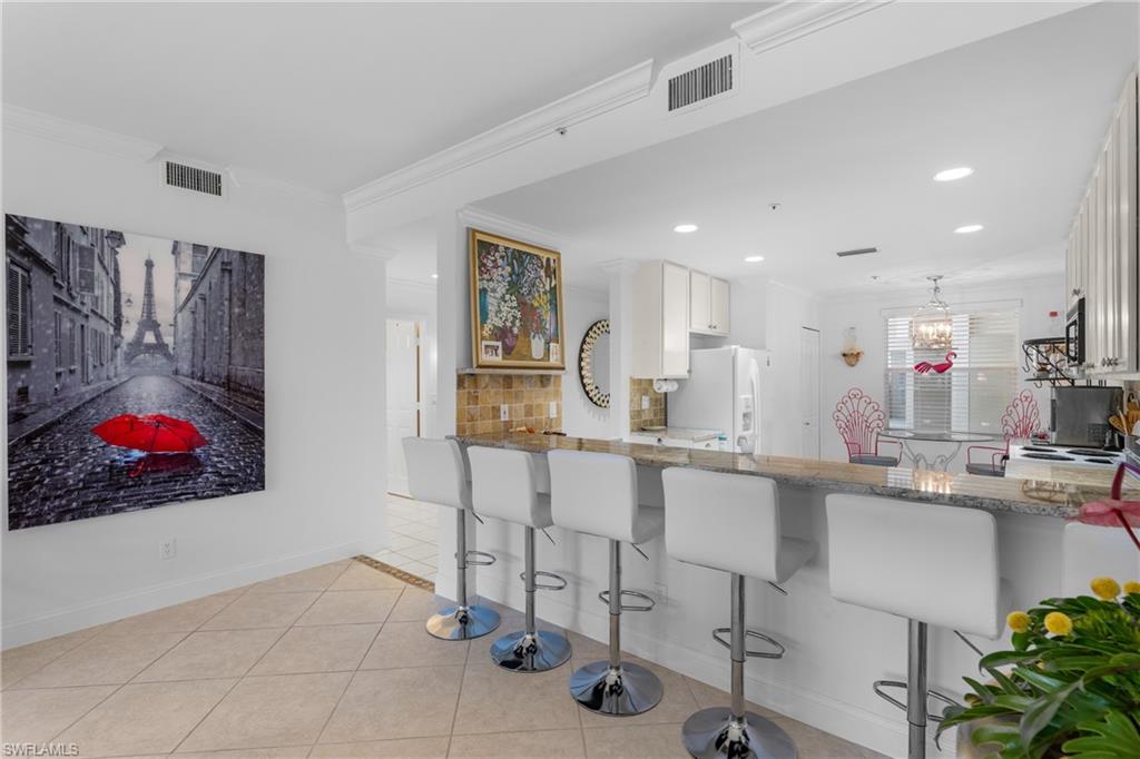 Kitchen featuring light stone countertops, light tile patterned floors, visible vents, and decorative backsplash