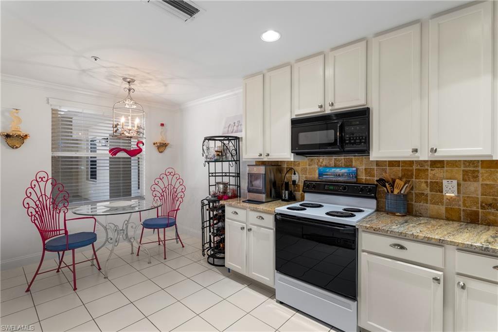 Kitchen with visible vents, baseboards, electric range oven, ornamental molding, and black microwave