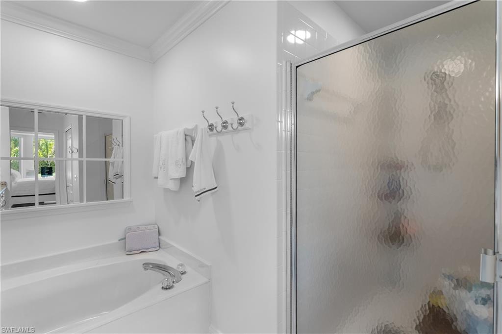 Full bath featuring ornamental molding, a garden tub, and a stall shower