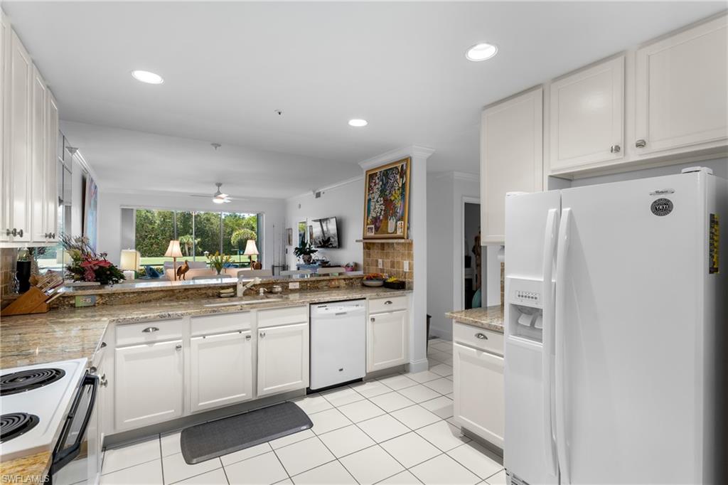 Kitchen featuring tasteful backsplash, white appliances, white cabinetry, a ceiling fan, and a sink