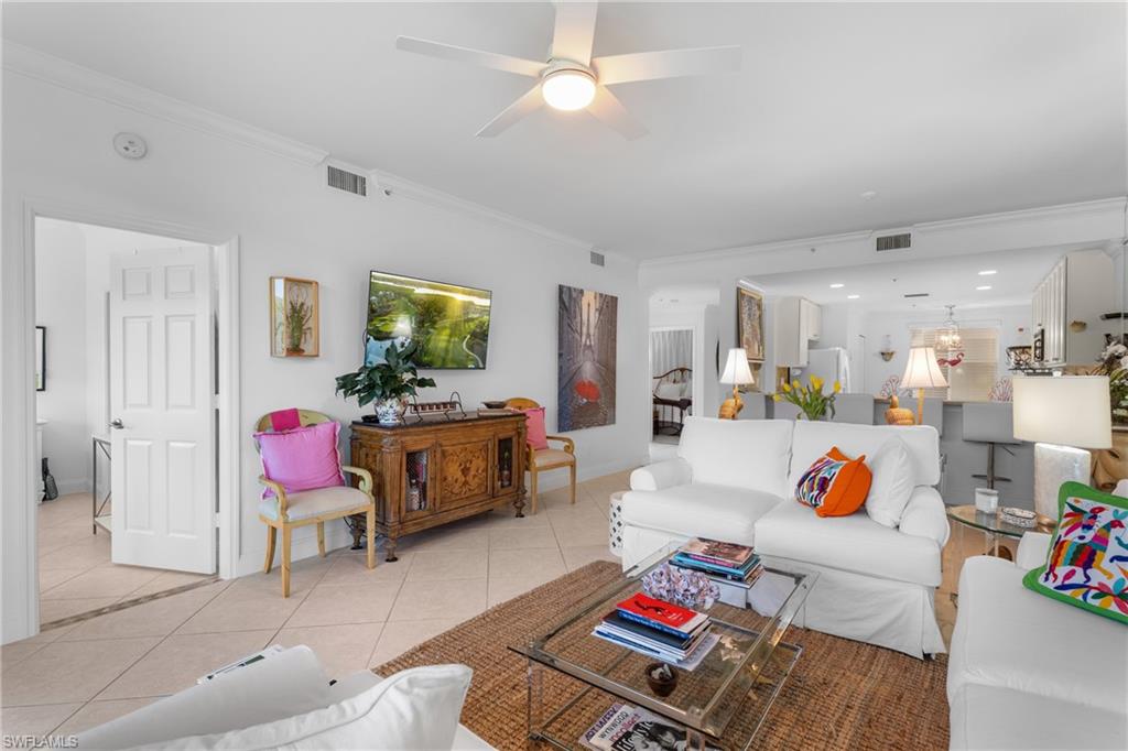 Living area with crown molding, light tile patterned flooring, ceiling fan, and visible vents