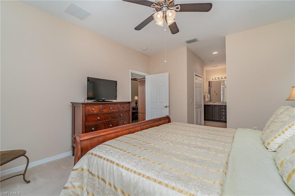 Bedroom featuring ceiling fan, light carpet, connected bathroom, and a closet