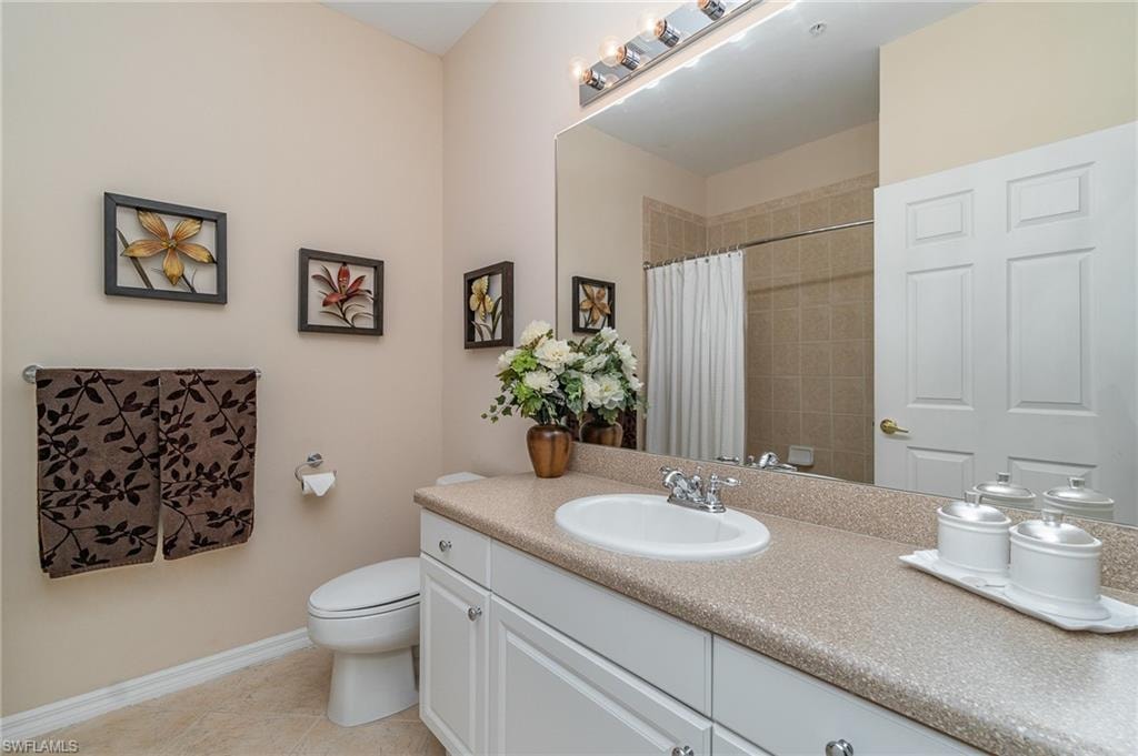 Bathroom featuring tile patterned flooring, vanity, toilet, and a shower with curtain