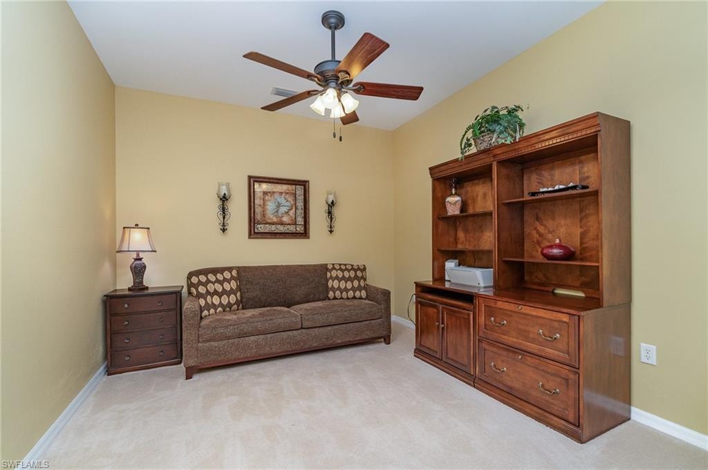 Living area featuring light carpet and ceiling fan