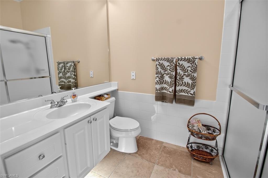 Full bath with vanity, a stall shower, tile walls, and wainscoting