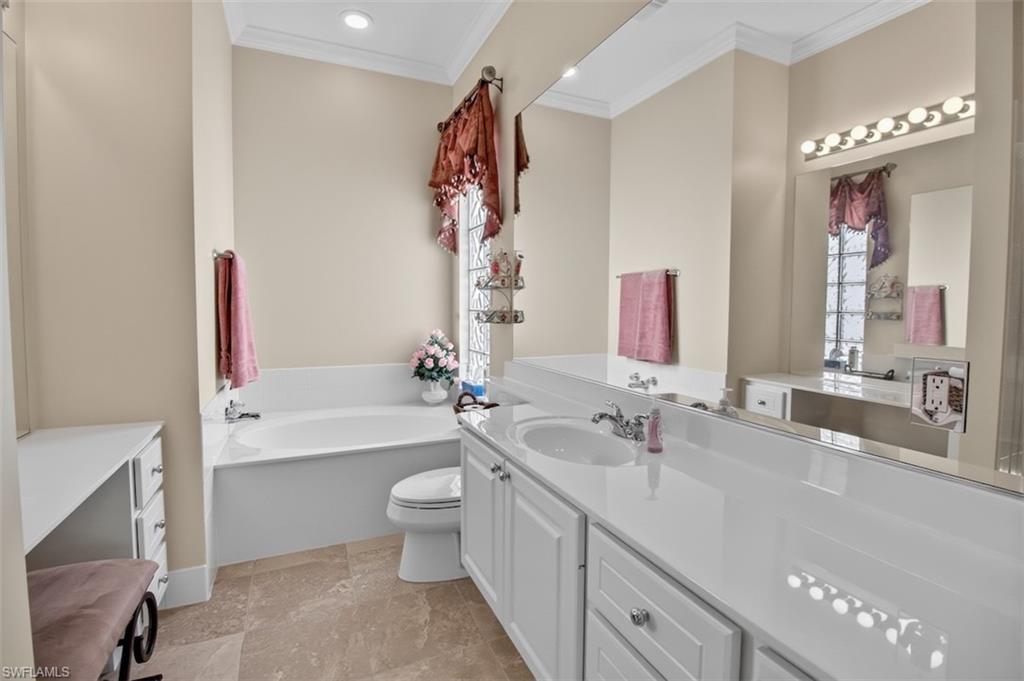 Full bathroom with vanity, ornamental molding, a garden tub, and recessed lighting
