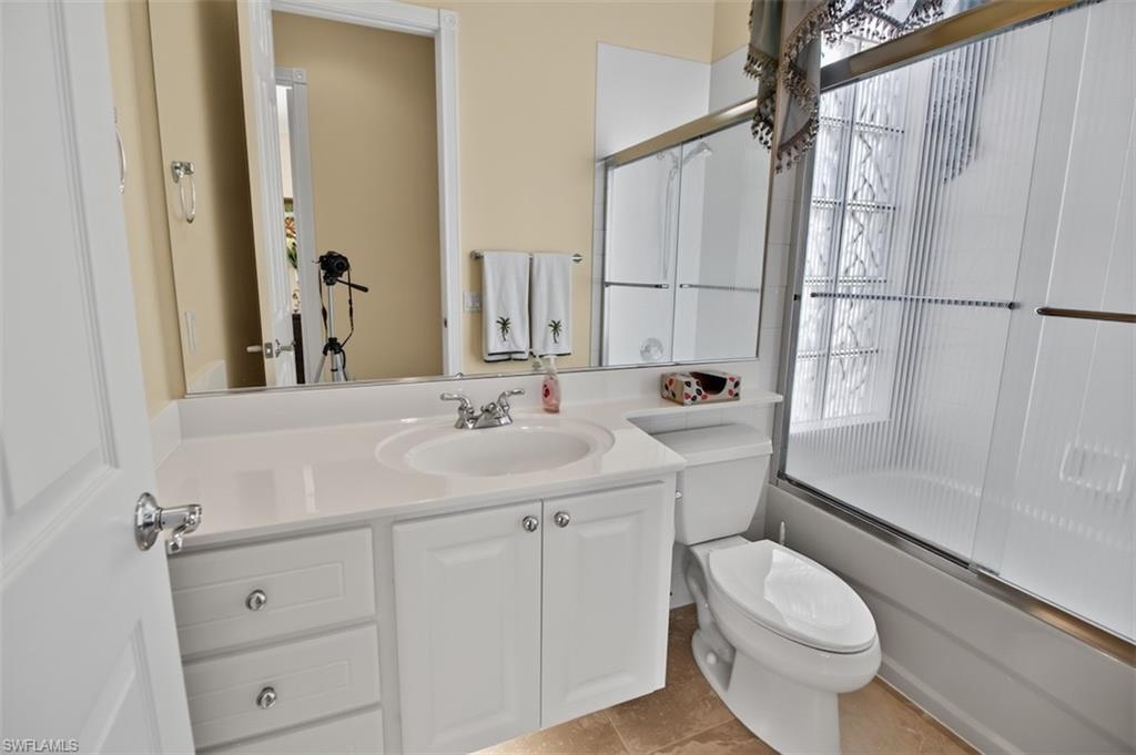 Full guest bathroom featuring vanity and shower / bath combination with glass door
