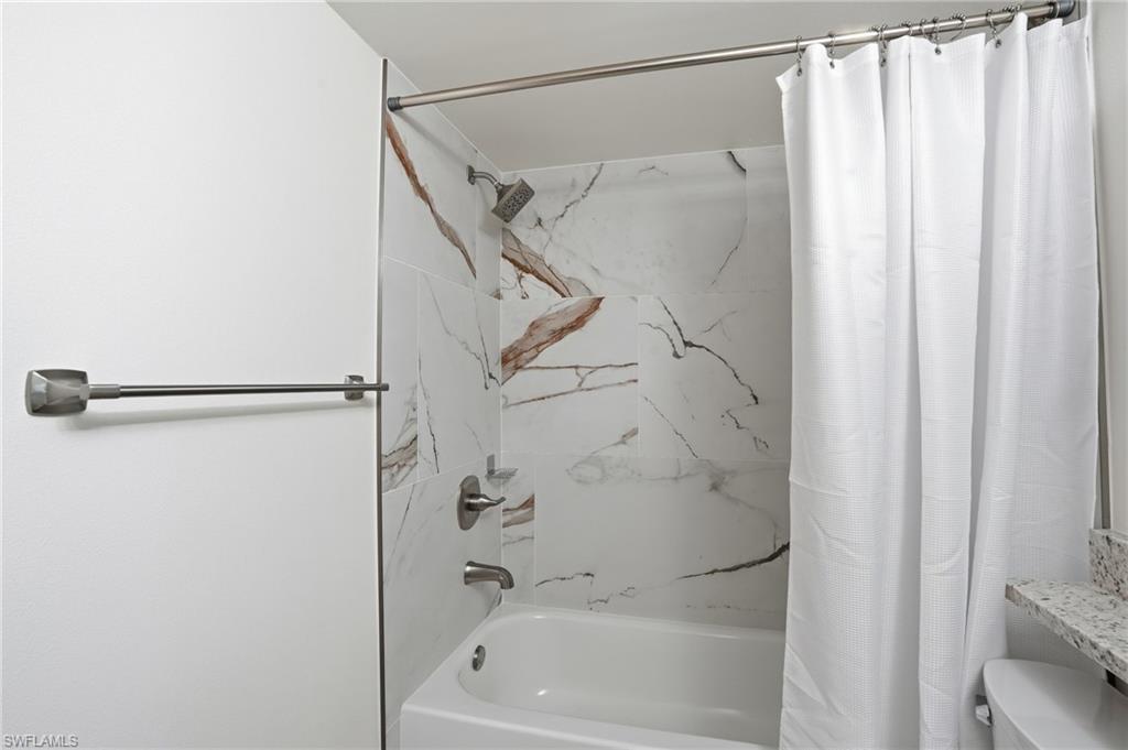 Bathroom featuring toilet and shower / tub combo with curtain - Virtually Edited Image