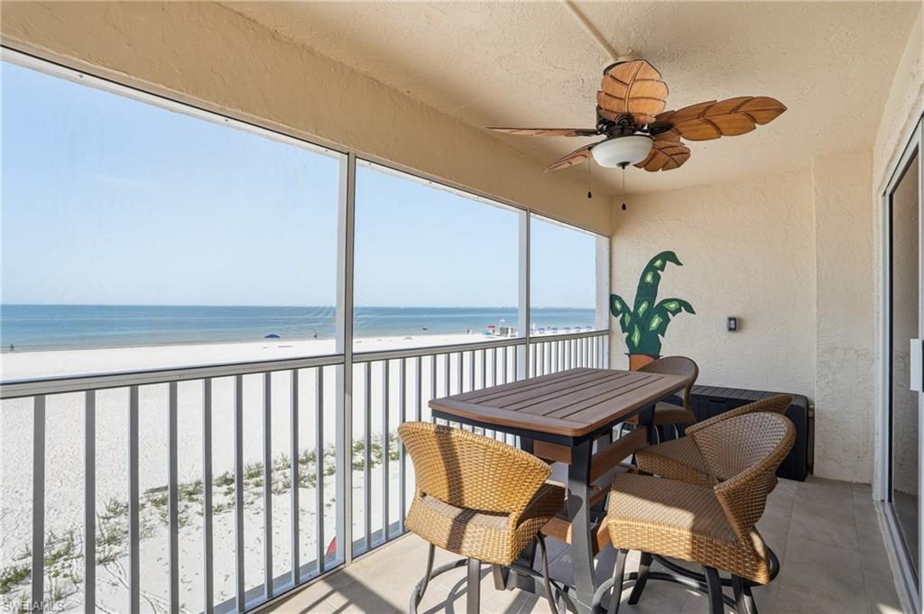 Sunroom / solarium with ceiling fan, view of water and beach, and a balcony - Virtually Edited Image