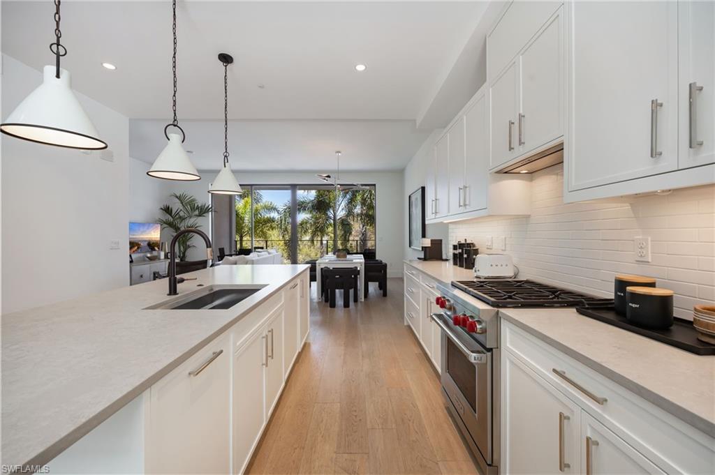 Kitchen featuring premium stove, white cabinets, light wood-type flooring, and pendant lighting