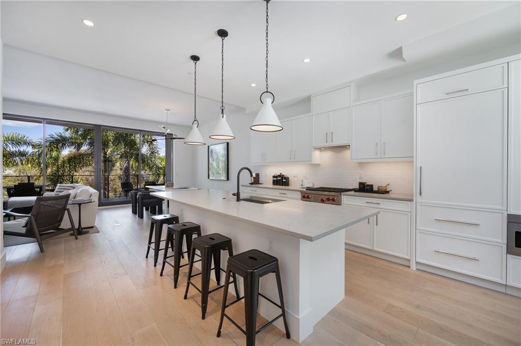 Kitchen with white cabinets, a breakfast bar, and an island with sink