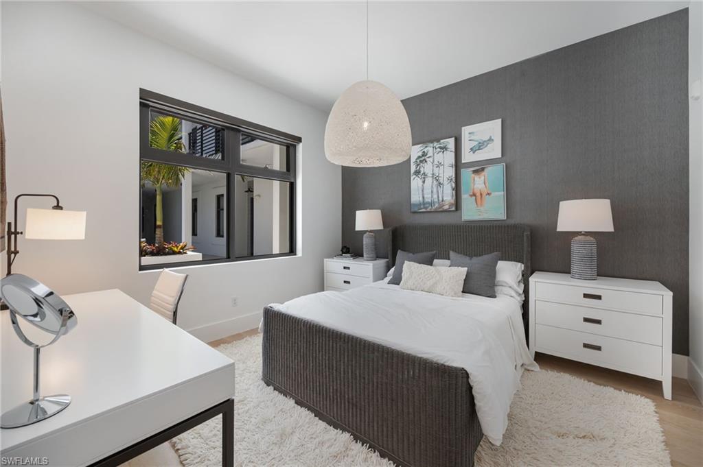 Bedroom featuring an accent wall, a desk, and light wood finished floors