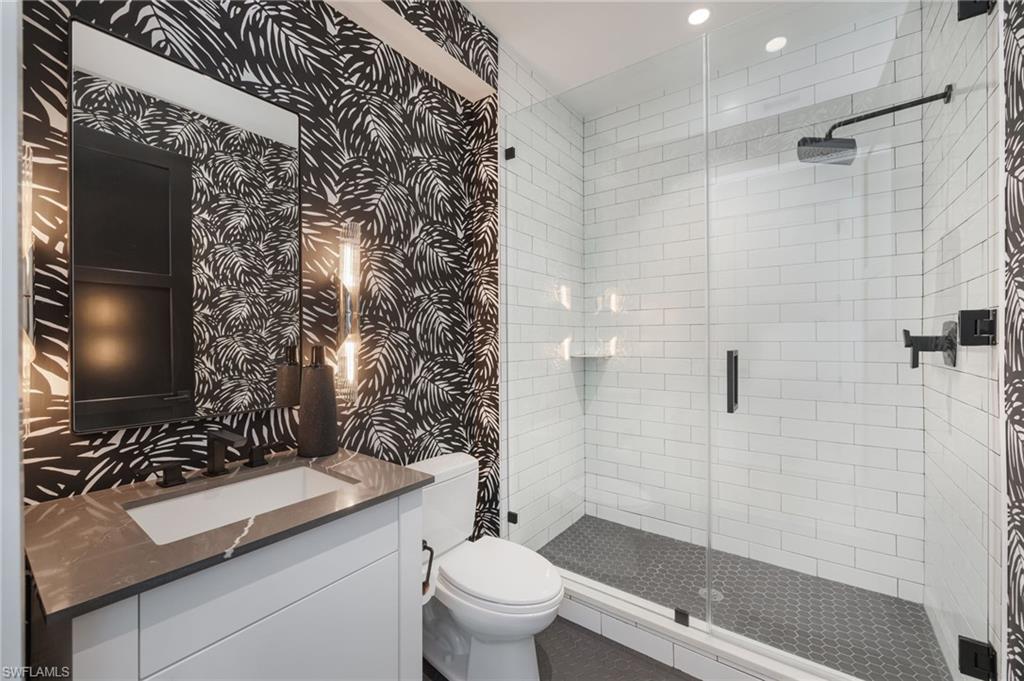 Bathroom with wallpapered walls, vanity, a shower stall, and recessed lighting