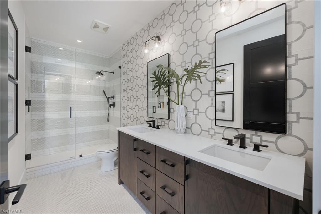 Bathroom with a stall shower, double vanity, and light tile patterned flooring