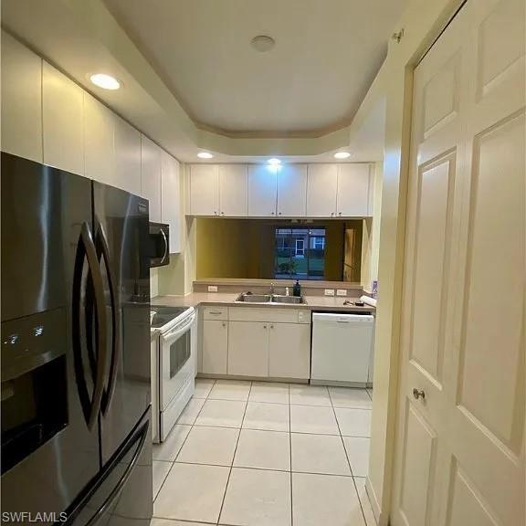 Kitchen with white appliances, white cabinetry, light tile patterned flooring, recessed lighting, and light countertops