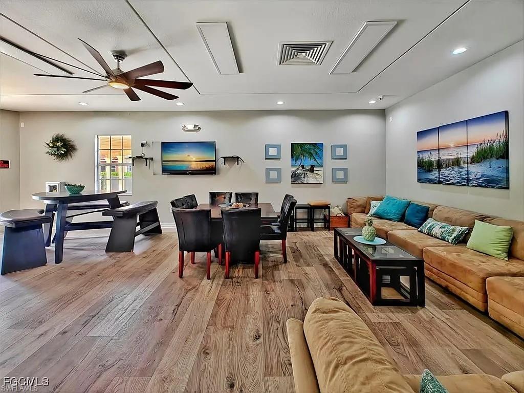 Living room with a ceiling fan, light wood-style flooring, and recessed lighting