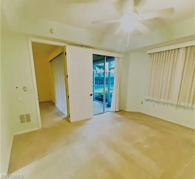 Empty room featuring a ceiling fan and light colored carpet