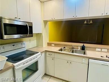 Kitchen with white appliances, light countertops, white cabinets, and light tile patterned flooring