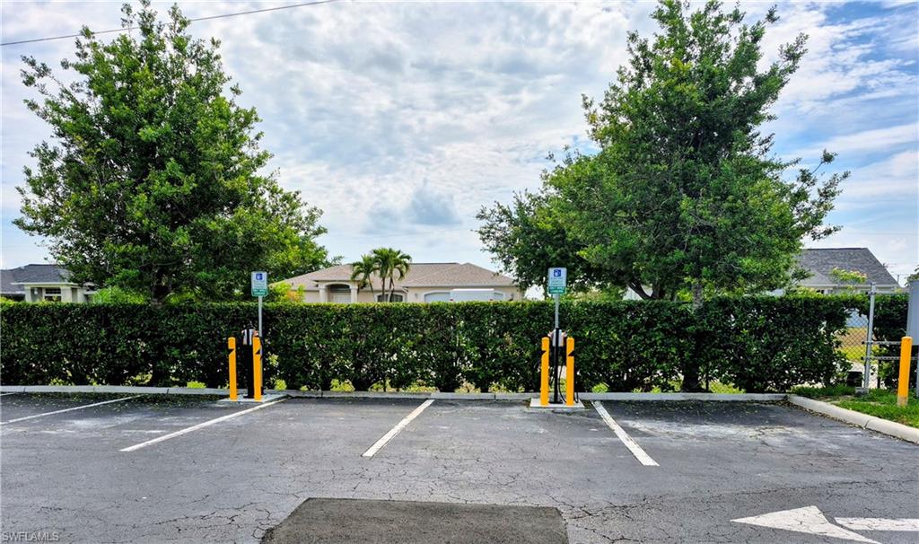 Dedicated electric vehicle charging stations, clearly marked parking spaces, and a manicured hedge border