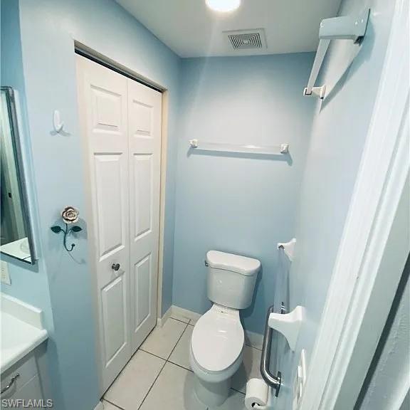 Bathroom with a closet, light tile patterned floors, and vanity