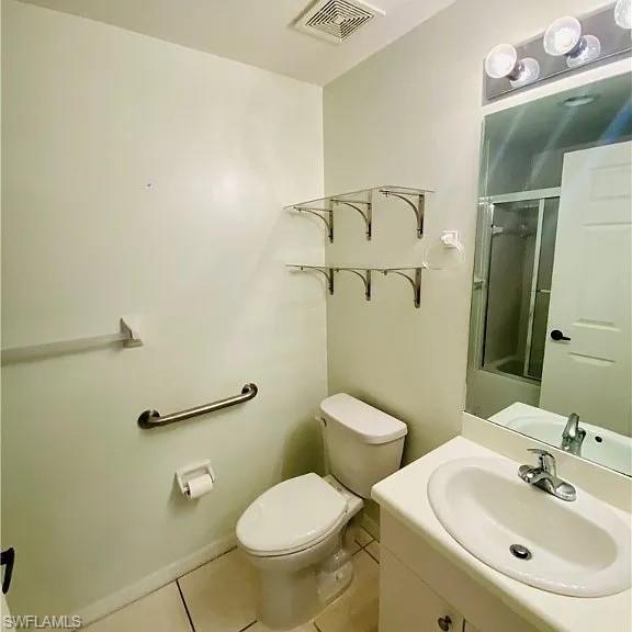 Full bathroom featuring a shower with door, vanity, and light tile patterned flooring