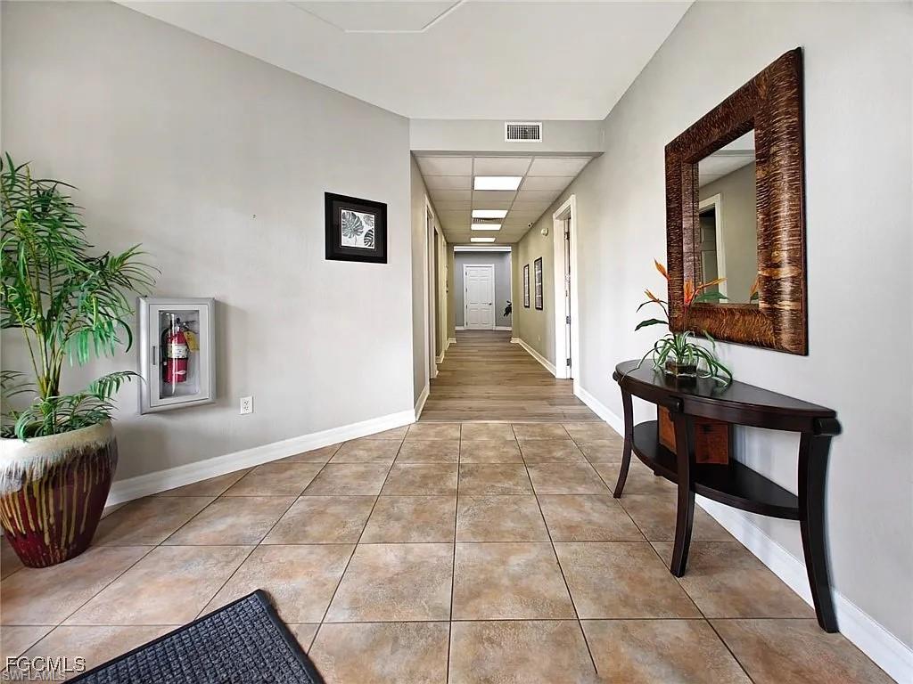 Hall featuring light tile patterned flooring and a paneled ceiling