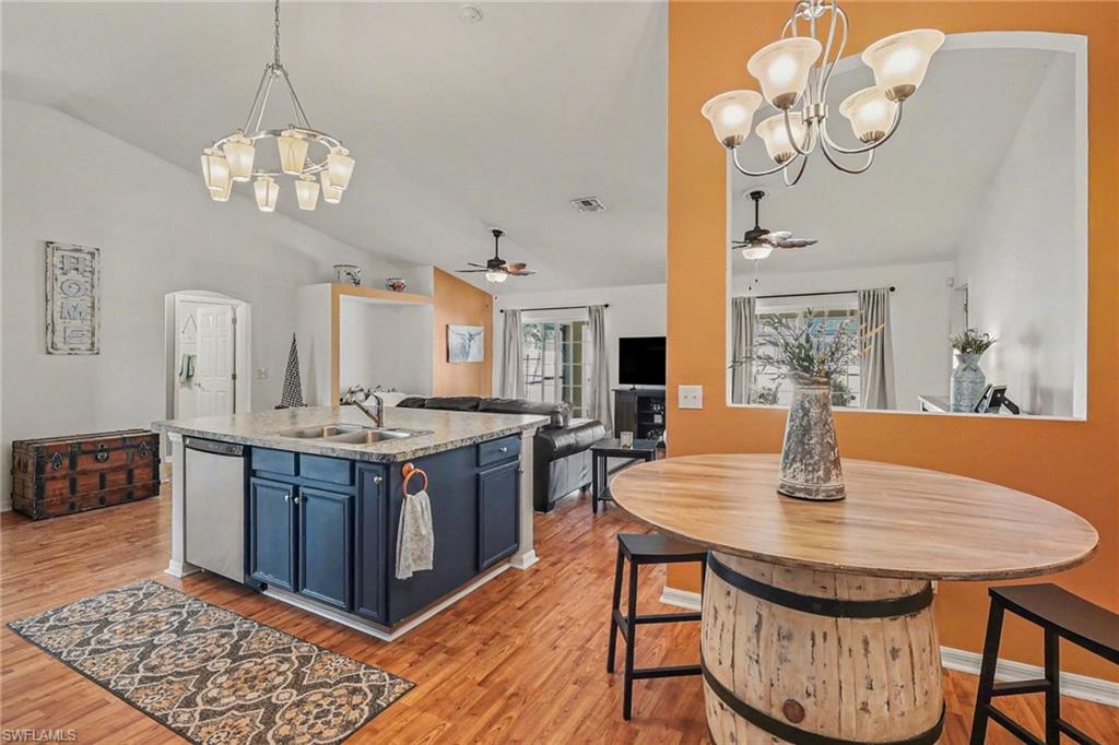 Kitchen with suspended lighting, ceiling fan, lofted ceiling, open floor plan, and a kitchen island with sink