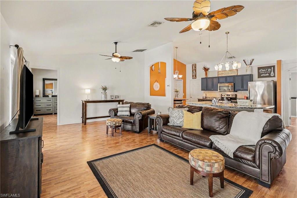 Living area featuring ceiling fan, suspended lighting, vaulted ceiling, and light wood finished floors