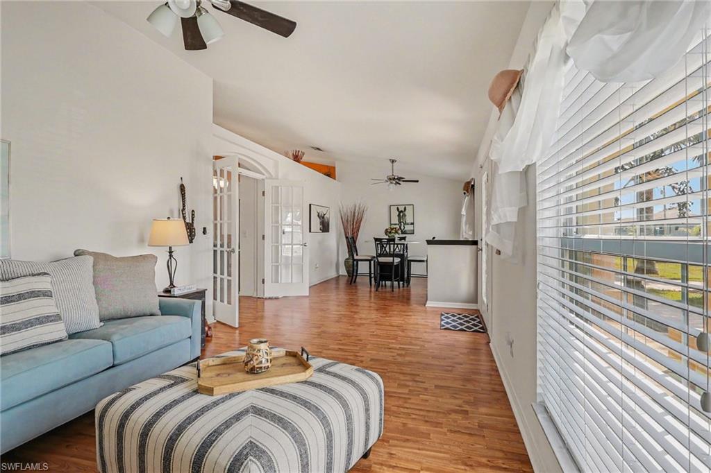 Living area featuring a ceiling fan, lofted ceiling, wood finished floors, and french doors