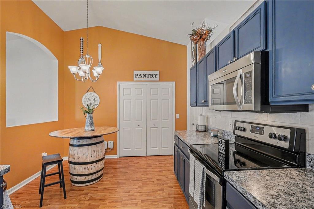 Kitchen with stainless steel appliances, lofted ceiling, light wood-type flooring, light countertops, and hanging lights