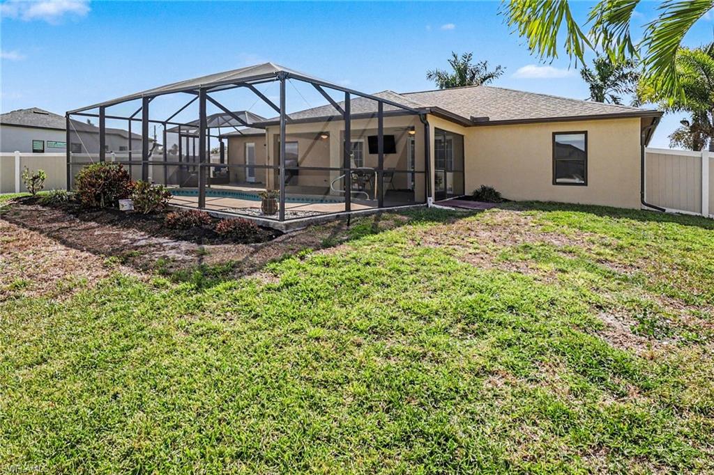 Rear view of property featuring a sunroom, a fenced backyard, glass enclosure, and stucco siding