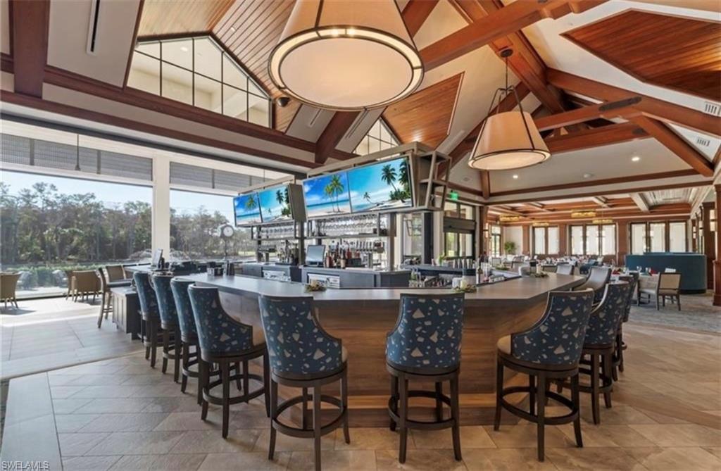 Bar featuring dark countertops, hanging light fixtures, and a high ceiling